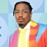 Nick Cannon smiling at a public event, wearing a patterned suit and tie. Teluguways.com