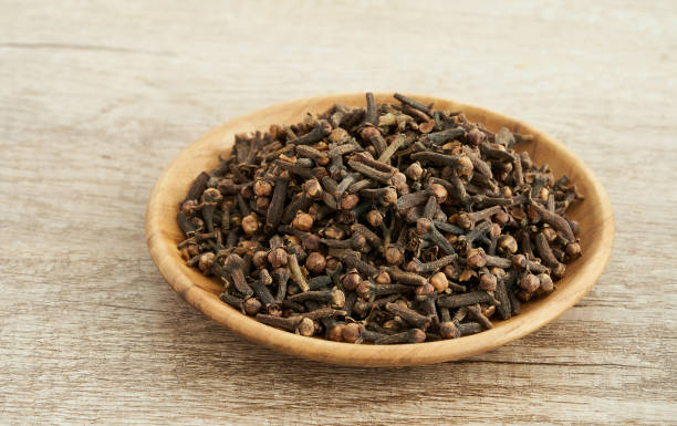 Two cloves on a wooden surface showcasing their health benefits, including improved digestion, boosted immunity, and antioxidant properties.